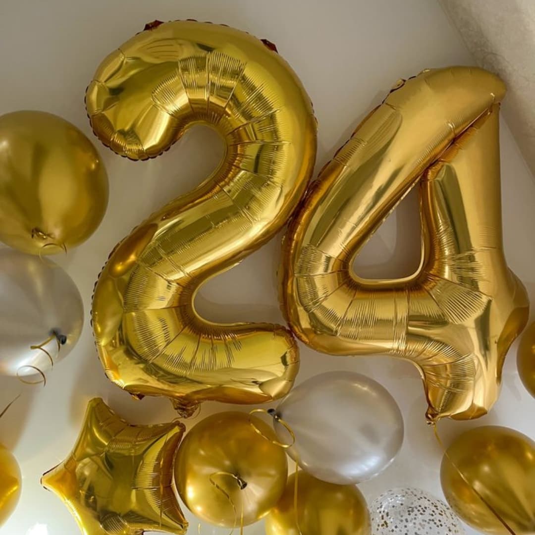 Globo metálico número 24 inflado con aire, colocado sobre mesa decorativa