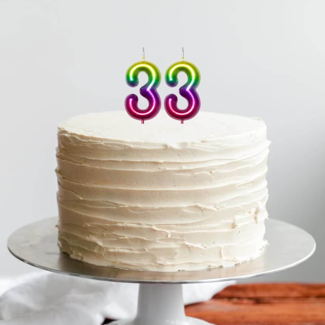 Decoración con velas metálicas número 3 en colores arcoíris sobre torta festiva
