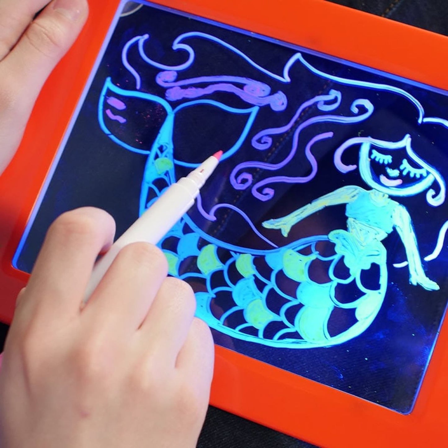 Niños usando la tableta MagicPad con entusiasmo en una mesa, creando dibujos coloridos.