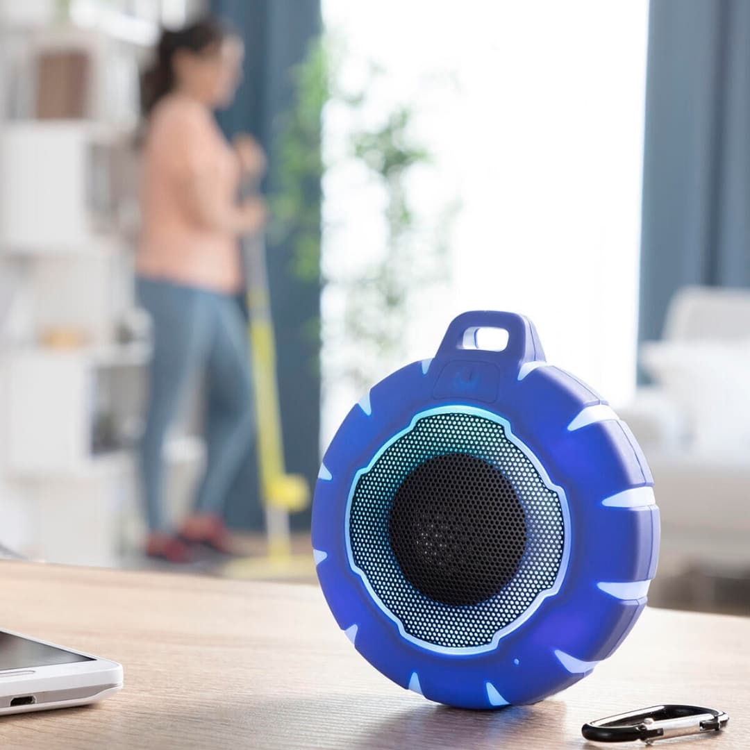 Vista lateral del altavoz flotante con botón multifunción y mosquetón metálico