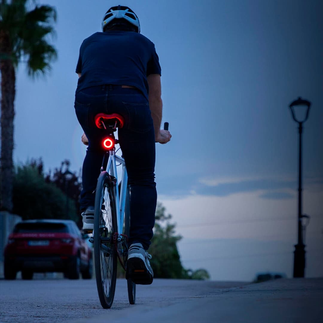 Ciclista utilizando luz trasera LED durante paseo nocturno en ciudad