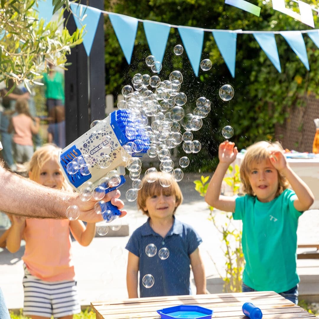 Niños jugando al aire libre con pistola de burbujas gigante y luces LED