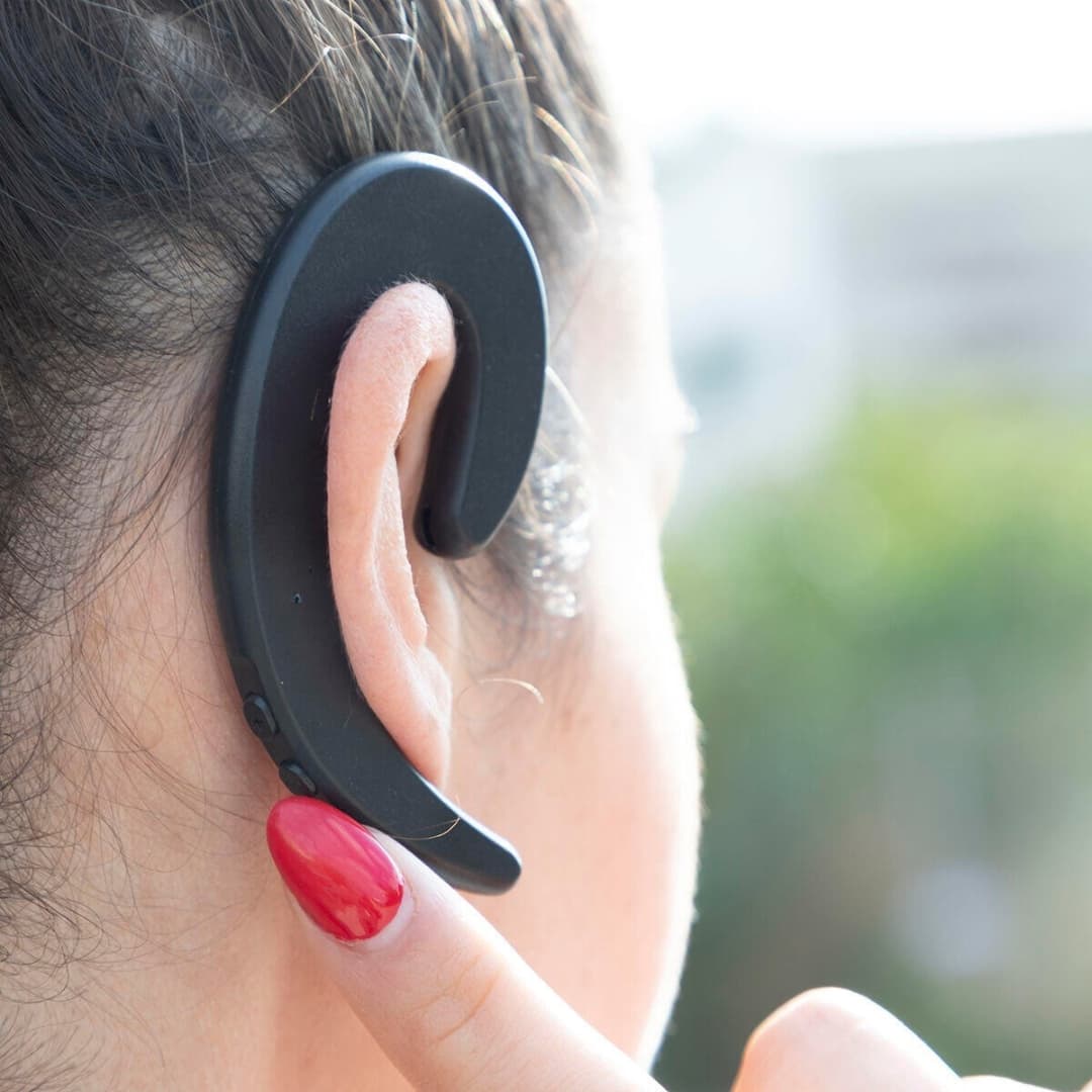 Auricular open-ear colocado en oreja derecha mostrando ajuste cómodo y seguro