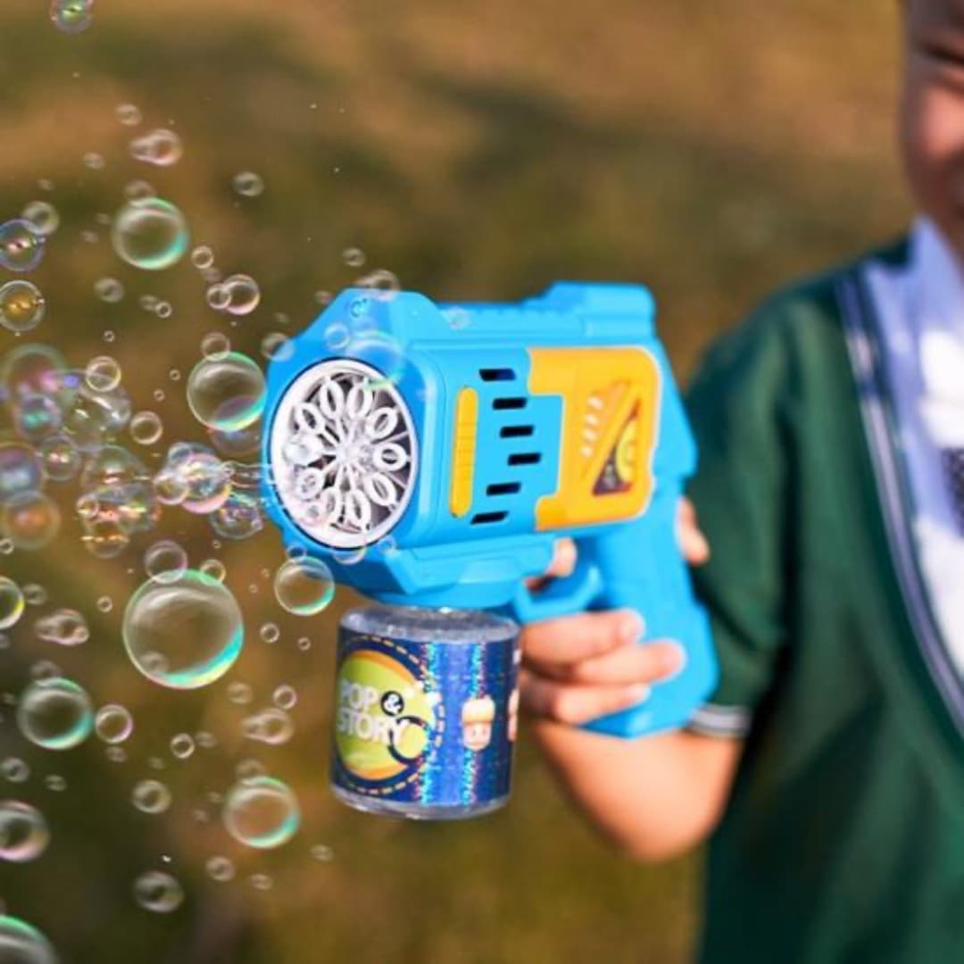 Niño feliz sosteniendo la máquina azul de burbujas en uso.