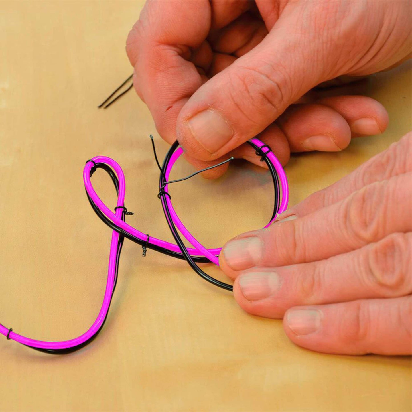 Mano preparando instalación del cable neón LED rosa flexible para personalización.