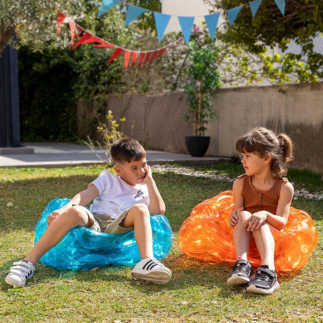Niños rodando y rebotando dentro de pelotas hinchables gigantes durante una fiesta