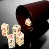 Juego de Dados con Cubilete sobre mesa de cristal Juego de dados con cubilete y cinco dados colocado sobre una mesa de cristal en ambiente elegante