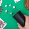 Juego de Dados con Cubilete en uso sobre mesa de juego Jugadores lanzando el juego de dados con cubilete y cinco dados sobre una mesa de juego durante una partida