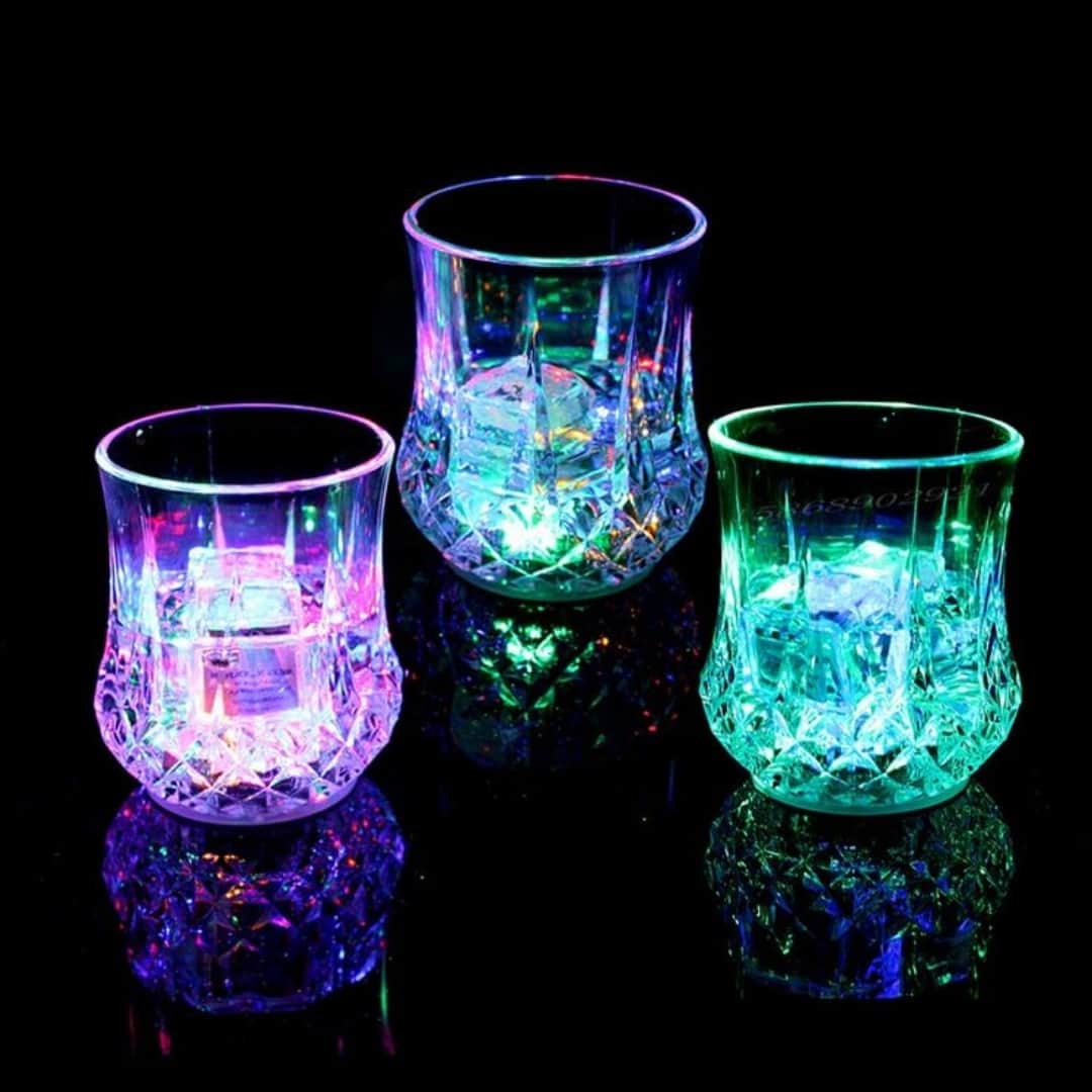 Tres vasos LED encendidos mostrando diferentes colores brillantes durante una fiesta nocturna