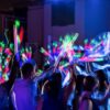 Familia usando palos de espuma LED multicolor encendidos durante una celebración nocturna