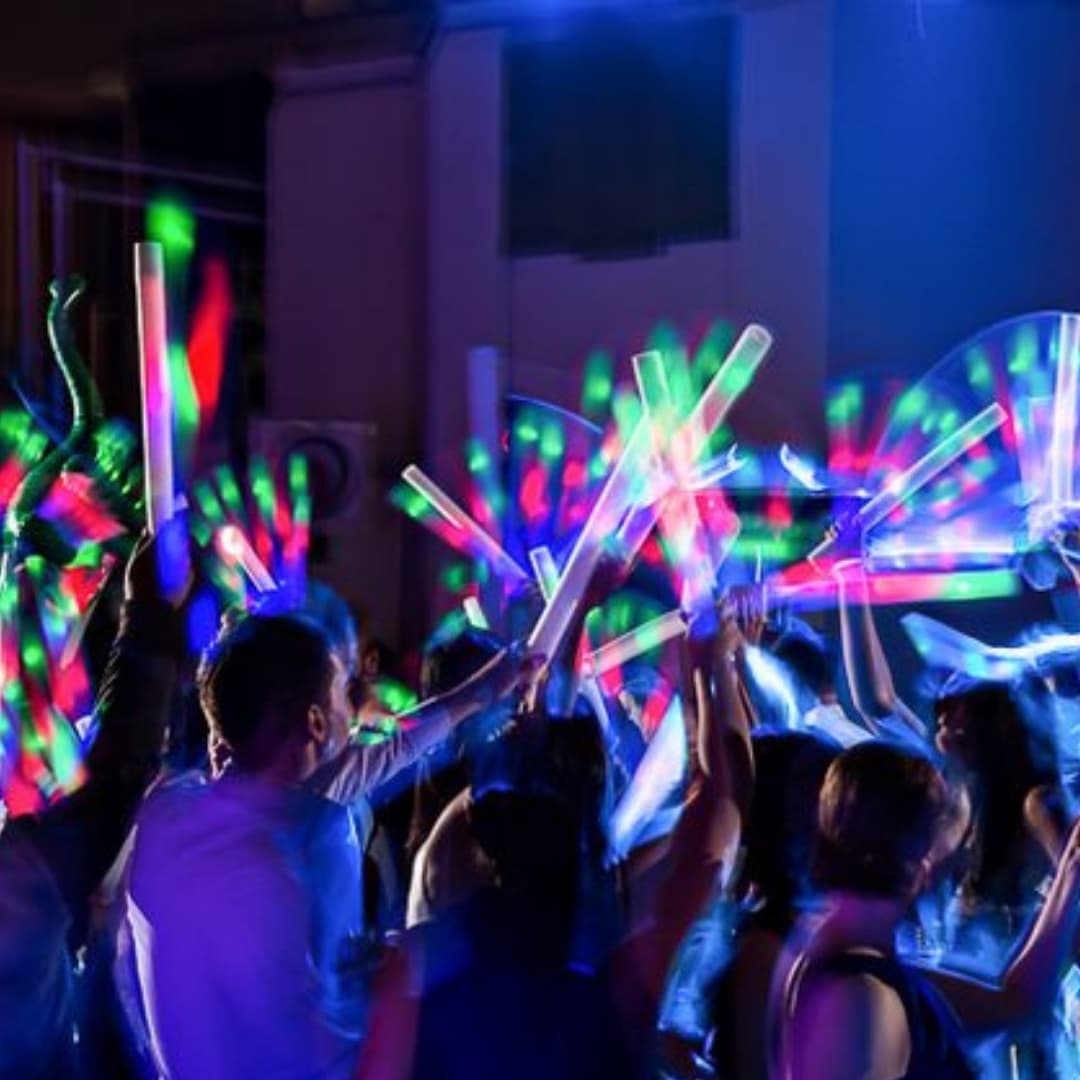 Familia usando palos de espuma LED multicolor encendidos durante una celebración nocturna