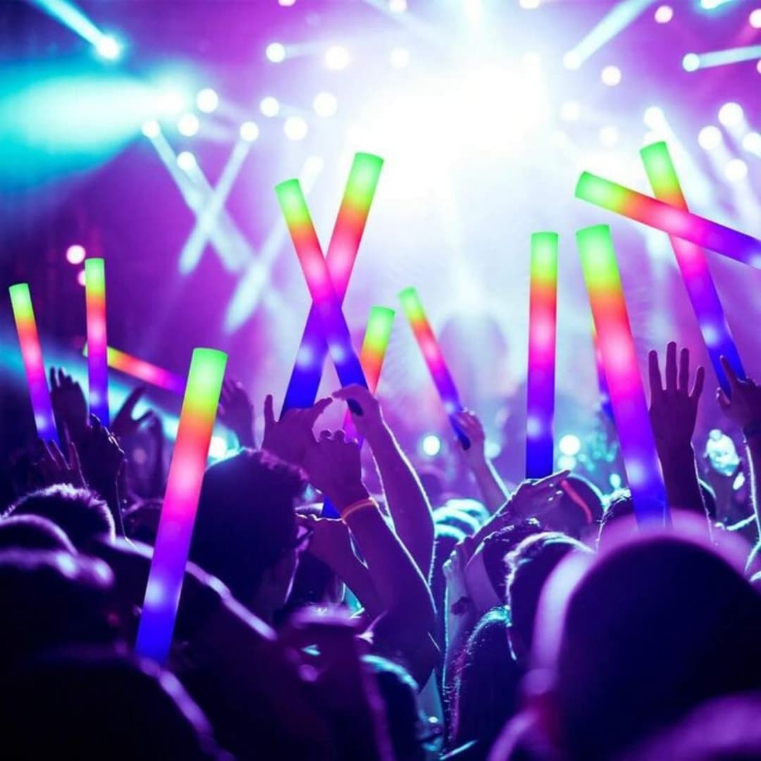 Palos de Espuma LED Foam Master 100 Ultra en uso durante una fiesta Grupo de personas bailando en una fiesta nocturna con palos de espuma LED Foam Master 100 Ultra encendidos en varios colores