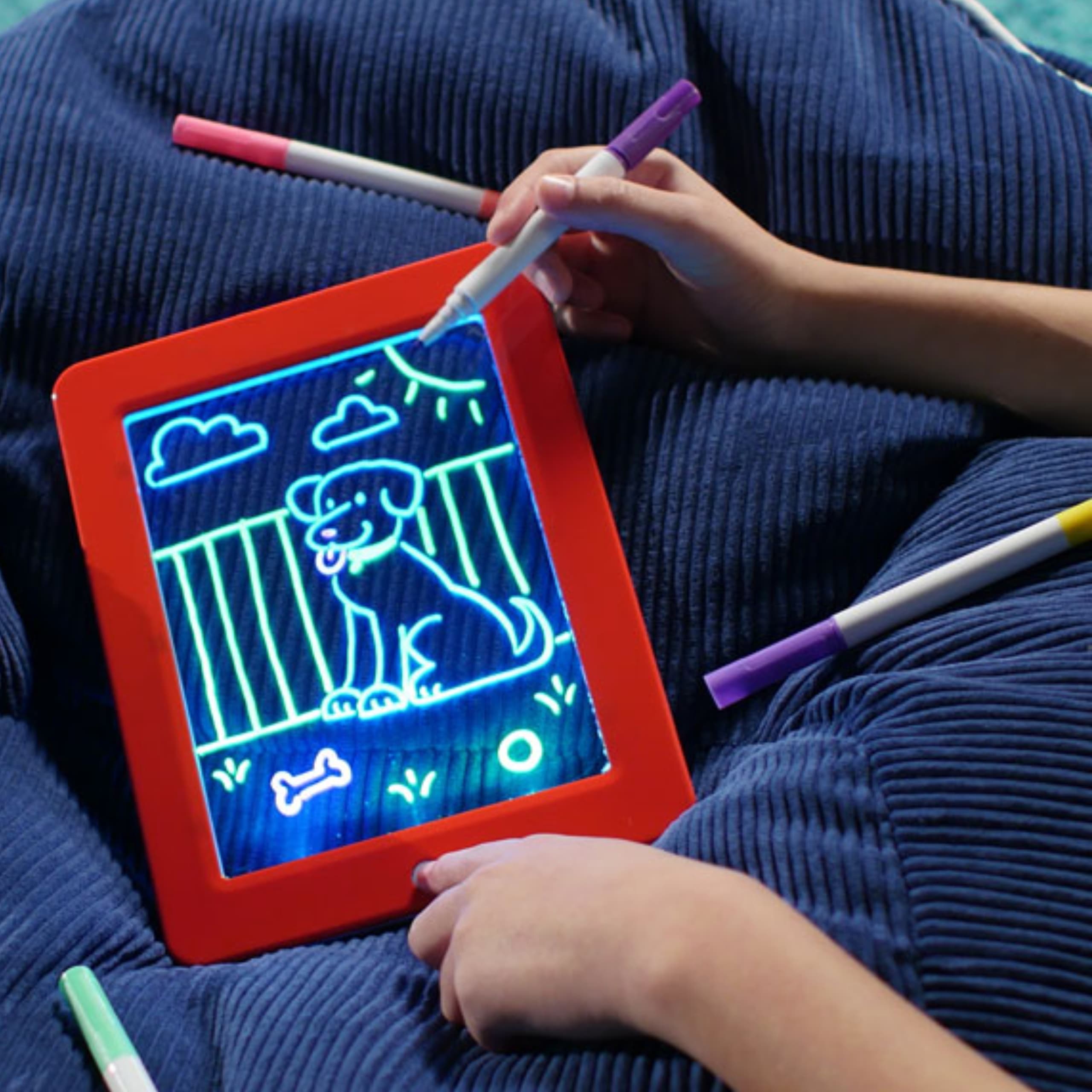 Niño dibujando en la tableta MagicPad con luces neón encendidas mostrando trazos brillantes y coloridos