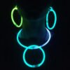 Mujer con pulseras luminosas GlowMaster Pro encendidas Mujer usando pulseras luminosas GlowMaster Pro encendidas en brazos y cuello durante una fiesta nocturna