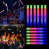 Jóvenes bailando con palos de espuma LED Mega Espuma 50 encendidos en colores neón durante una fiesta