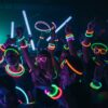Jóvenes en concierto usando pulseras luminosas Opti Glow multicolor durante una fiesta nocturna
