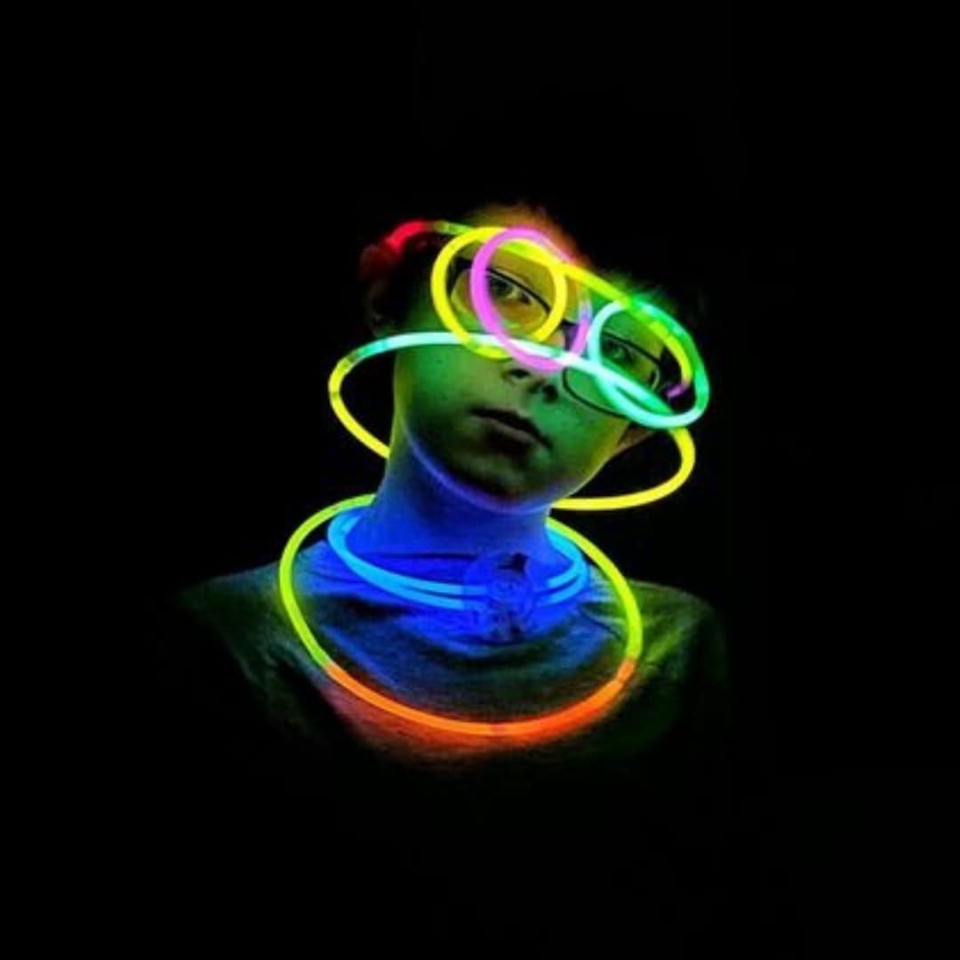 Niño usando barras luminosas Lumina Pro encendidas en colores neón durante una fiesta nocturna