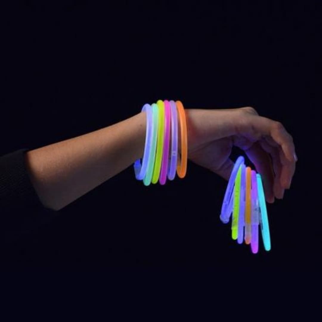 Mano con pulseras luminosas GlowMaster Pro encendidas Mano mostrando pulseras luminosas GlowMaster Pro encendidas con colores intensos en ambiente oscuro