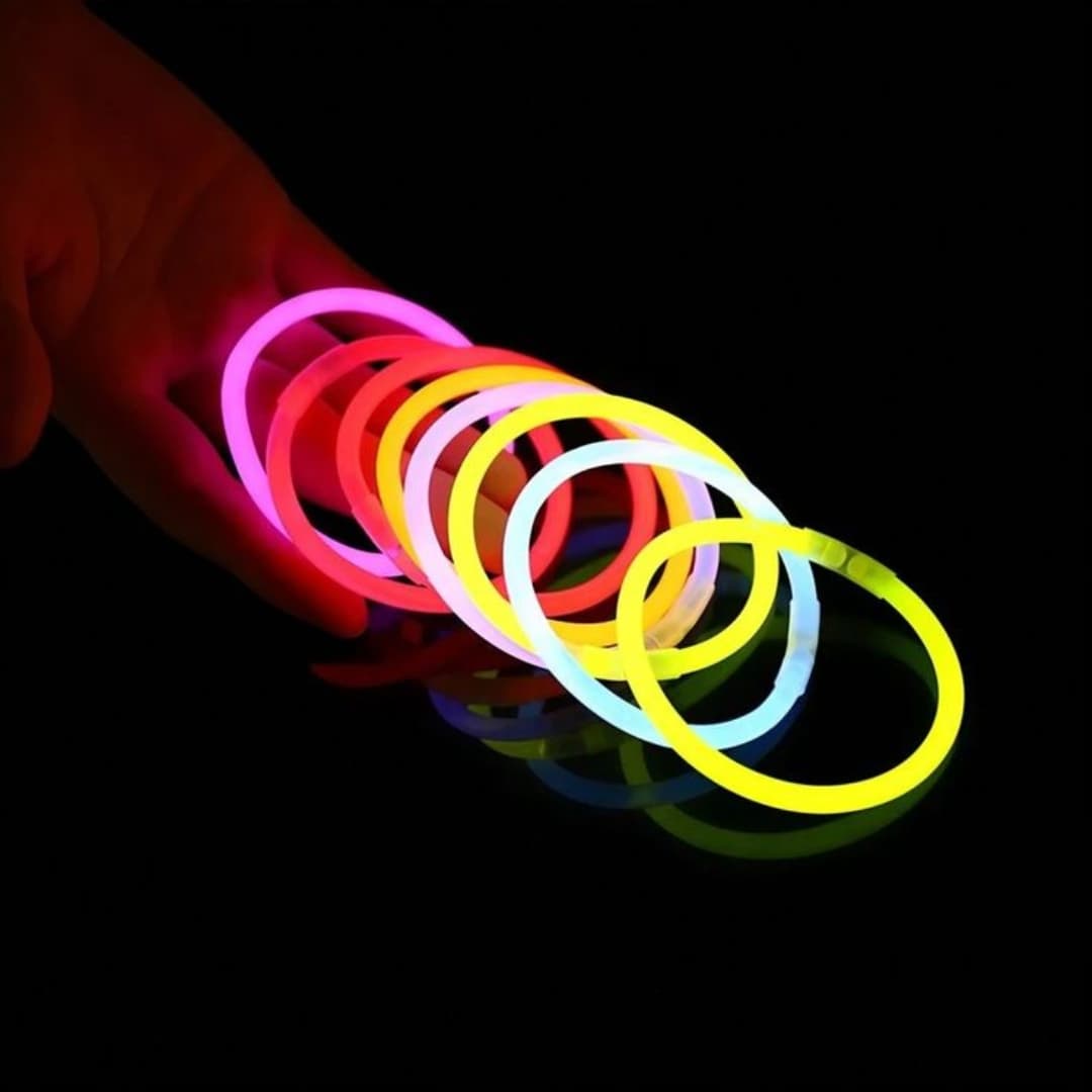 Pulseras Lumi Flex sobre mesa iluminada en fiesta nocturna Pulseras fluorescentes Lumi Flex encendidas sobre una mesa en ambiente nocturno durante una fiesta