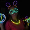 Chica usando pulseras fluorescentes Opti Glow como collares, gafas y accesorios luminosos en una fiesta