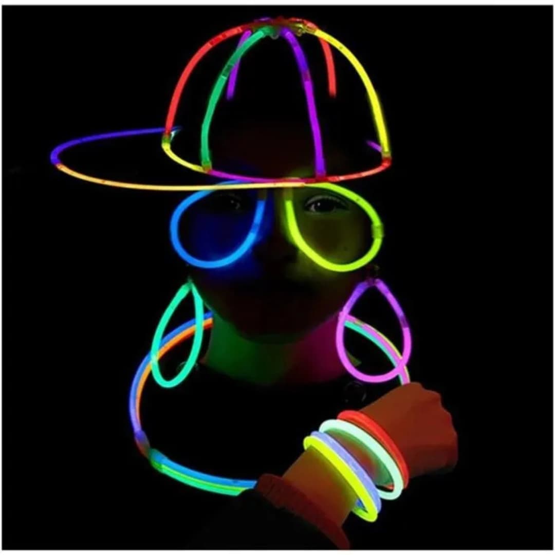 Chico usando pulseras luminosas Opti Glow como brazaletes, collares y accesorios fluorescentes en evento nocturno