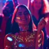 Chica usando LumiGlow Pro – Gel Glitter UV Biodegradable en fiesta Chica en una fiesta con gel glitter UV biodegradable LumiGlow Pro aplicado en rostro y cuerpo bajo luces de neón