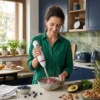 Batidora ergonómica para smoothies saludables Mujer preparando un smoothie de frutos rojos y espinacas con una batidora de mano ergonómica en una cocina moderna.