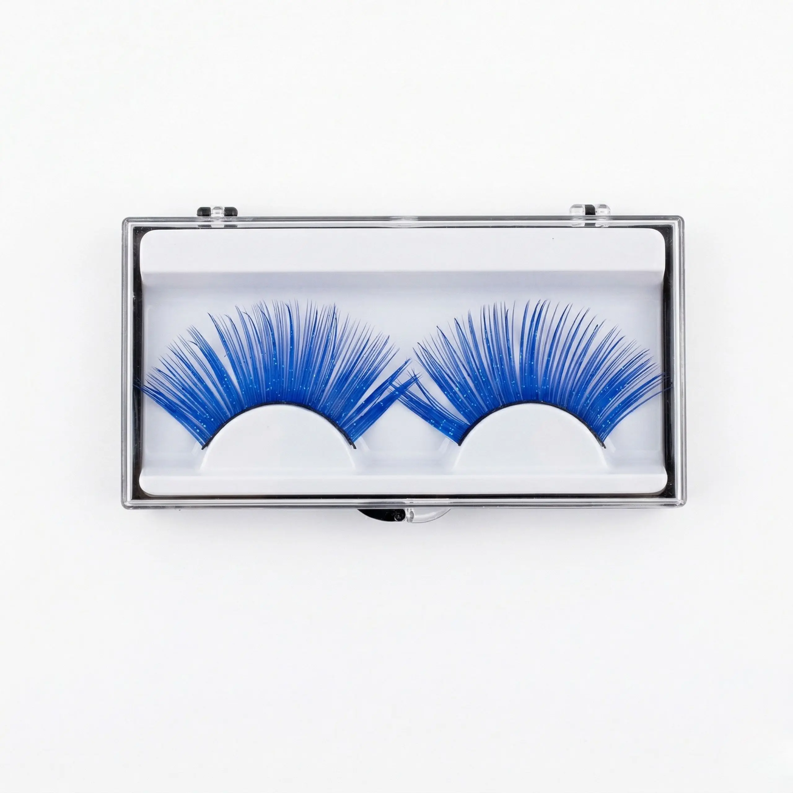Un par de pestañas postizas tupidas de color azul eléctrico presentadas en un estuche transparente con base blanca sobre fondo blanco