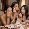 Maquillaje Versátil 3 en 1 en Uso Tres mujeres aplicando el stick de maquillaje como sombra de ojos, rubor en las mejillas y labial de larga duración frente a un espejo.