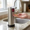 Persona usando dispensador de jabón automático en una cocina moderna para evitar la contaminación cruzada al cocinar.