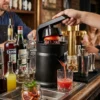 Barman utilizando el exprimidor de cítricos profesional en una barra de bar para extraer zumo fresco de naranja sanguina para cócteles.