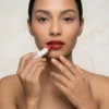 Aplicación de Labial Mate de Alta Pigmentación Primer plano de mujer aplicando barra de maquillaje roja en los labios mostrando la alta pigmentación y precisión del crayón.