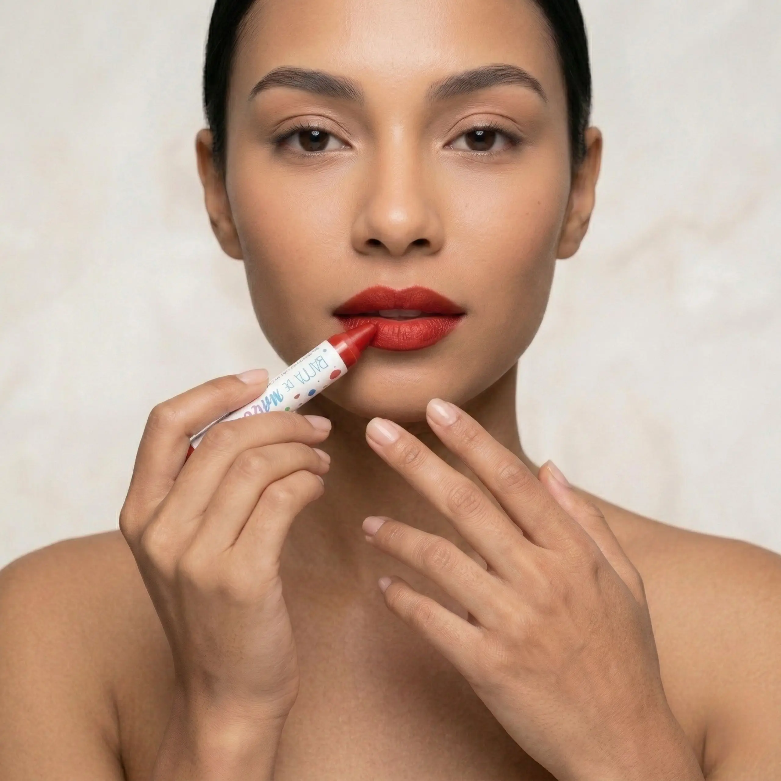 Aplicación de Labial Mate de Alta Pigmentación Primer plano de mujer aplicando barra de maquillaje roja en los labios mostrando la alta pigmentación y precisión del crayón.