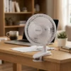 Mini Ventilador para Teletrabajo y Oficina Mini ventilador blanco DVtec de 6 pulgadas sujeto a un escritorio de madera junto a una laptop, ideal para refrescar el área de trabajo sin ruido.