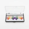 Pestañas postizas arcoíris de colores vibrantes en su caja de almacenamiento transparente sobre fondo blanco profesional.