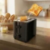 Tostadora ExtraHouse 700W con Salto Automático Tostadora de pan negra de 700W marca ExtraHouse con dos rebanadas de pan tostado saltando mediante el sistema de rebote automático.