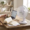 Ventilador Compacto para Zona de Trabajo Ventilador pequeño de mesa DVTECH en un escritorio de madera junto a un ordenador y libros, ideal para estudiar o teletrabajar.