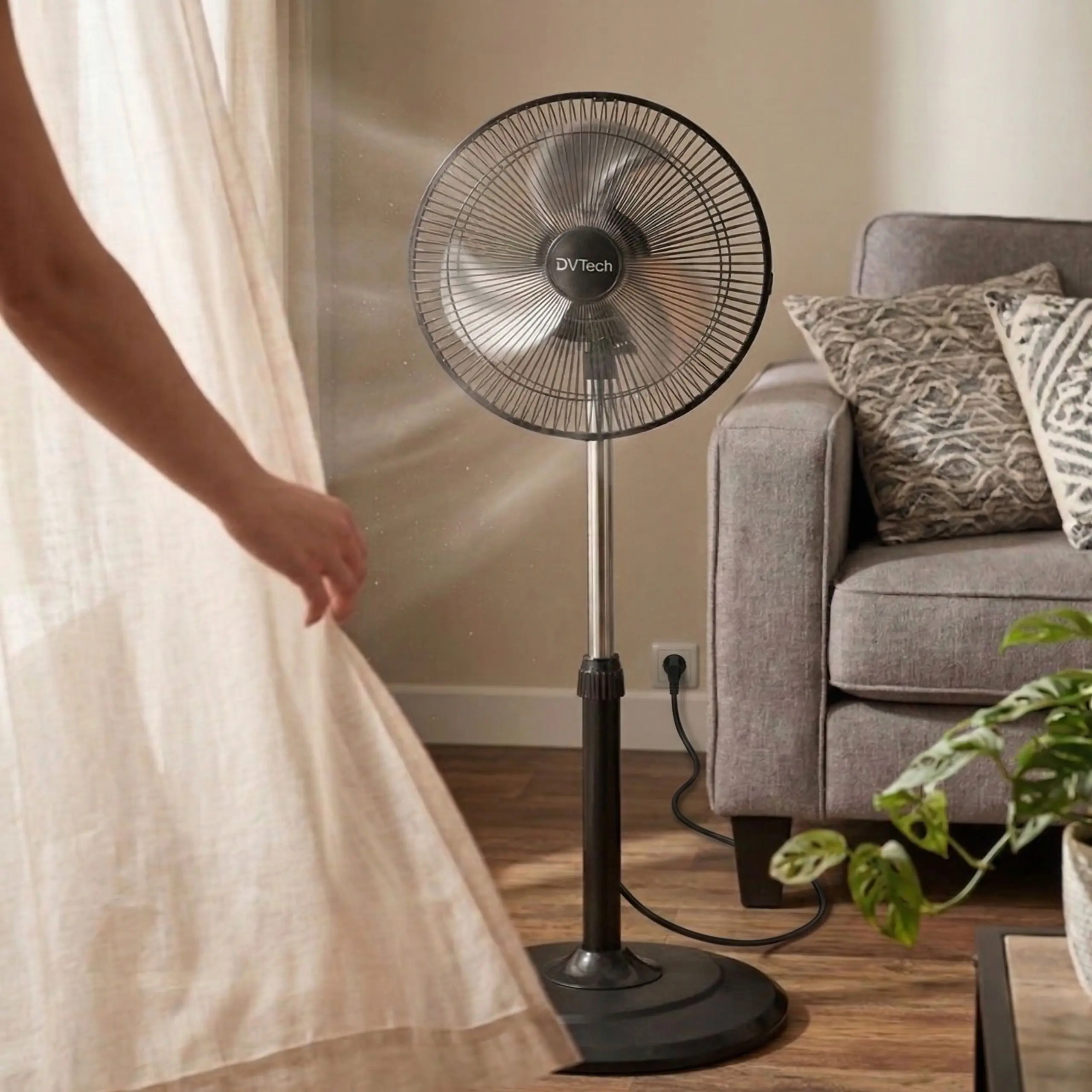 Ventilador DVTech en Sala de Estar Ventilador de pie negro junto a un sofá en un salón, refrescando el ambiente con un flujo de aire potente y silencioso.
